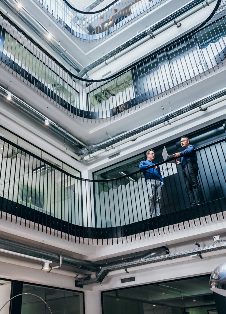 Collegas praten met elkaar op de gallerij van een kantoorgebouw