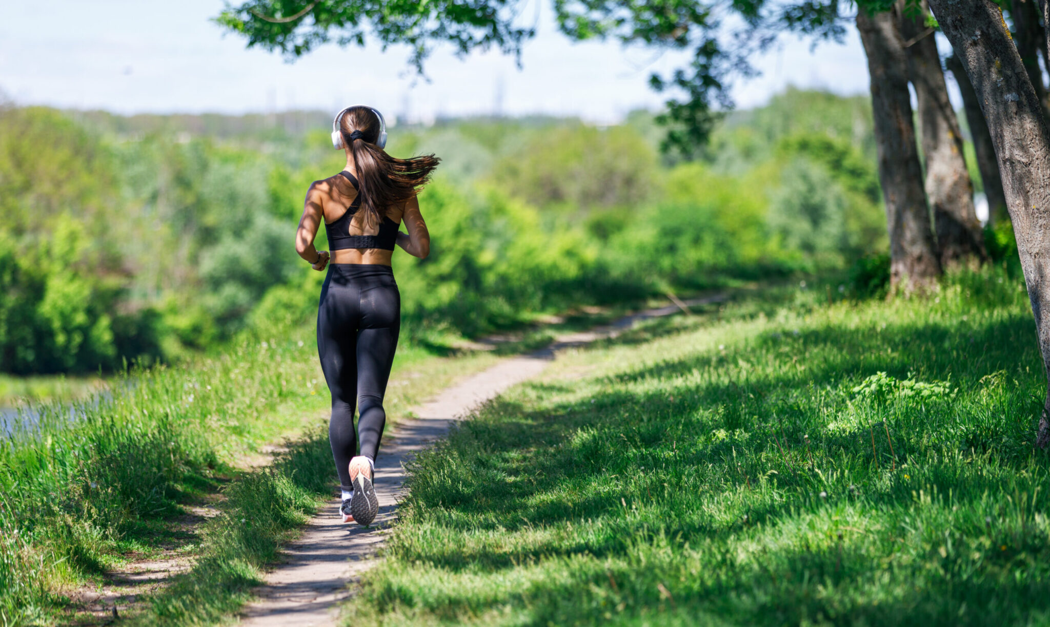 Young fitness woman jogging in park at sunny morning. Sporty girl running through the park