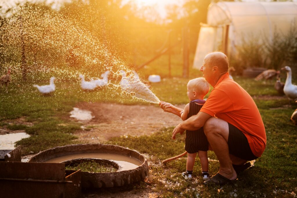 Man met peuter in de tuin spelen met water