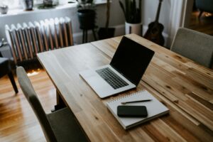 Tafel met daarom een laptop en een schrijfblokje met pen